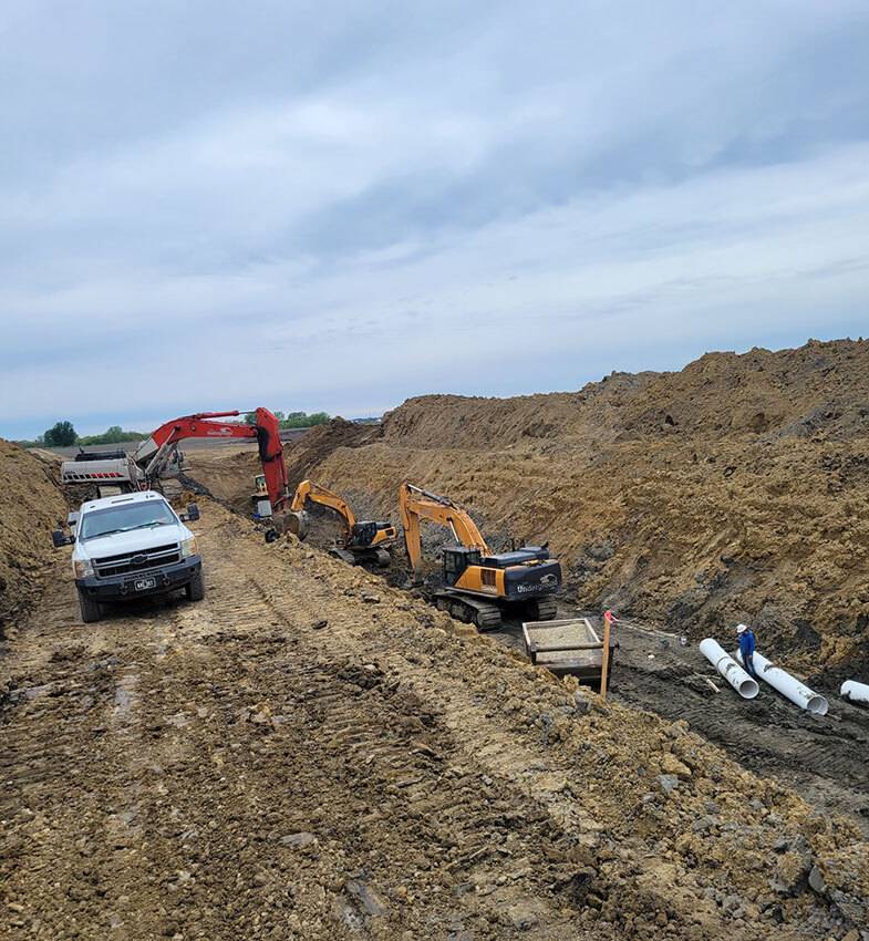 Three excavators dig along a trench at one of The Underground Company's utility project sites.